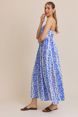 woman wearing a blue and white floral maxi dress with spaghetti straps and a flowy silhouette