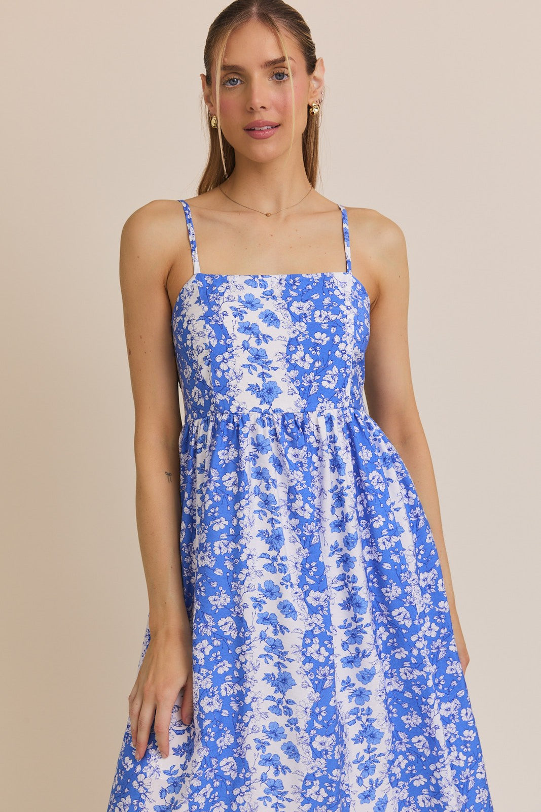 woman wearing a blue floral print spaghetti strap dress with a fitted bodice and flowy skirt