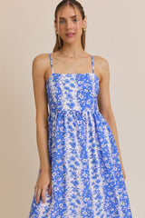 woman wearing a blue floral print spaghetti strap dress with a fitted bodice and flowy skirt