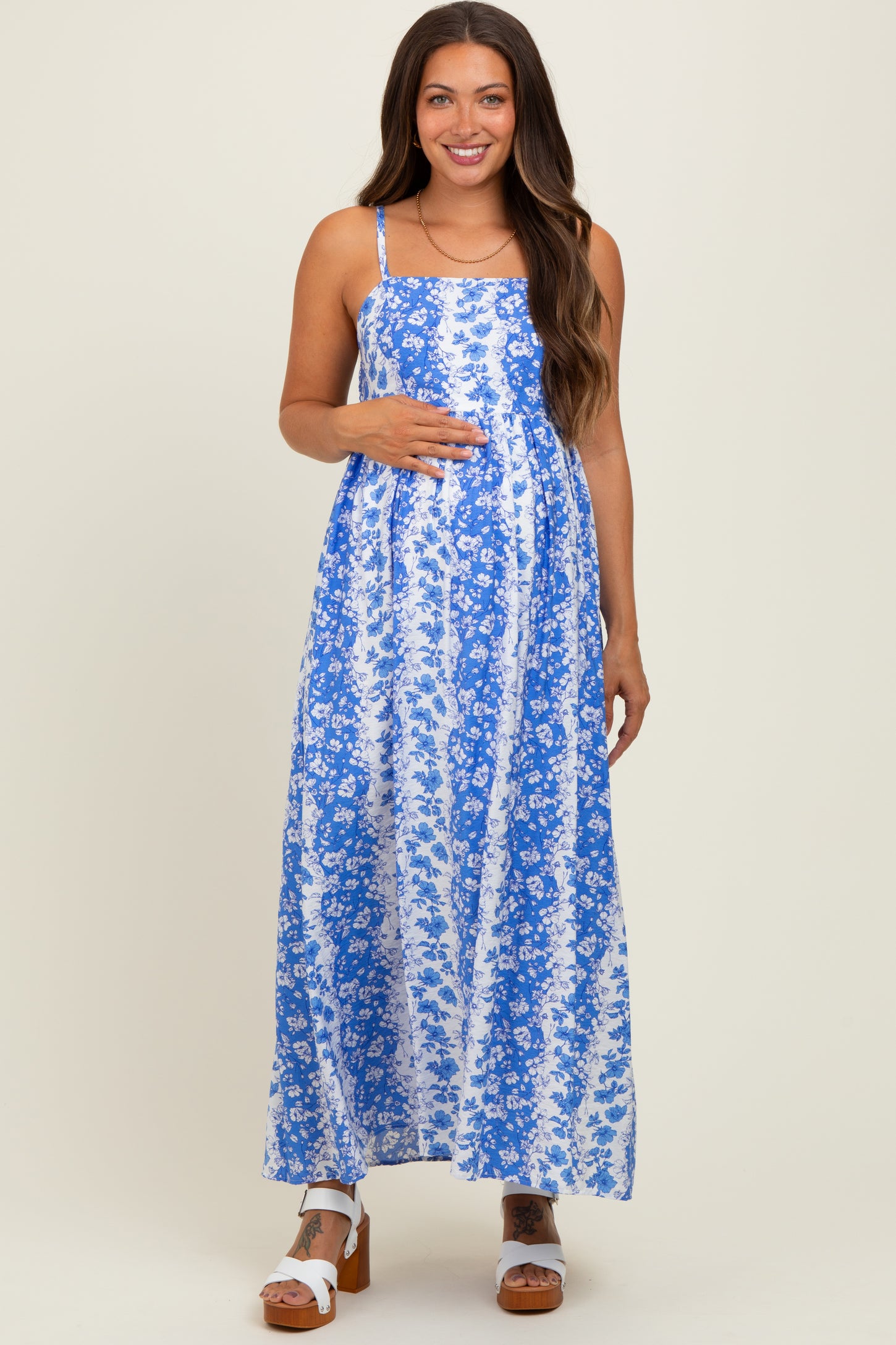 woman wearing a blue floral maternity maxi dress and holding her baby bump
