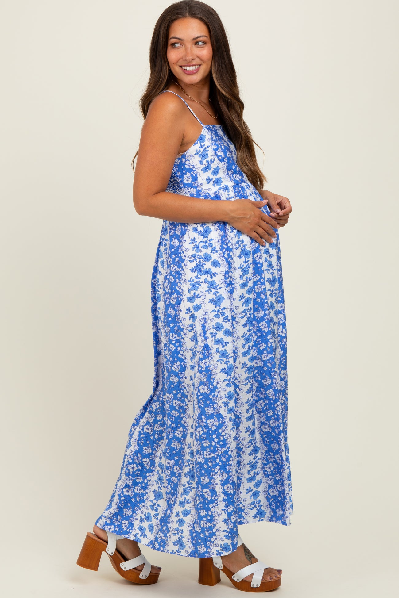 woman wearing a blue floral maternity maxi dress and holding her baby bump