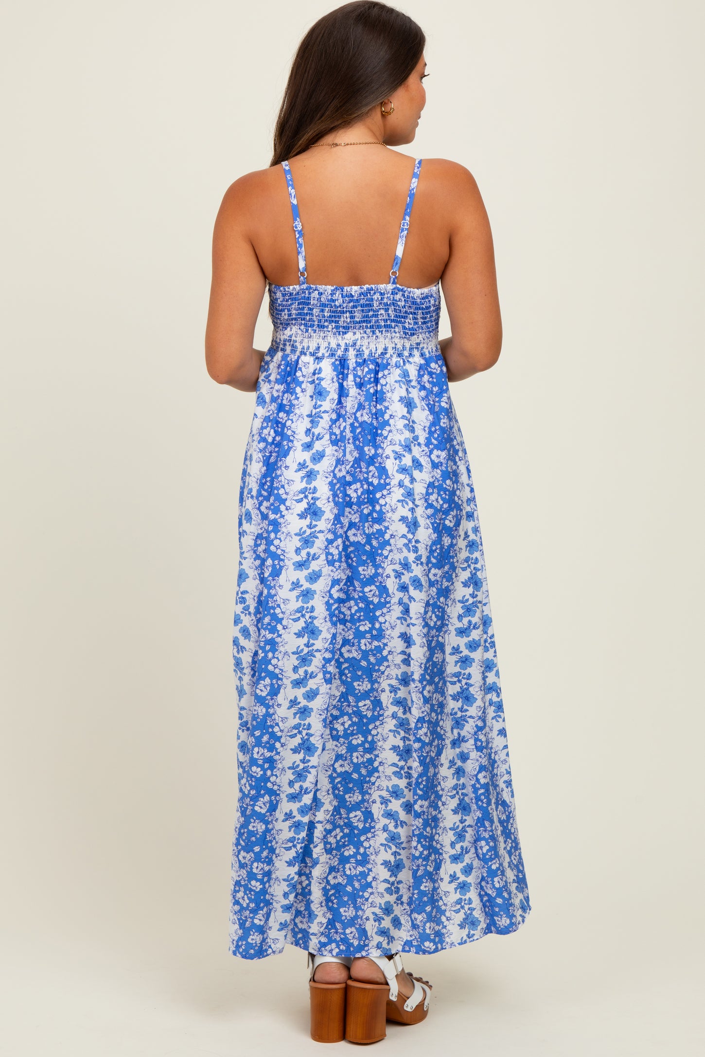 woman wearing a blue floral maternity maxi dress with a smocked back and thin straps, showing her back