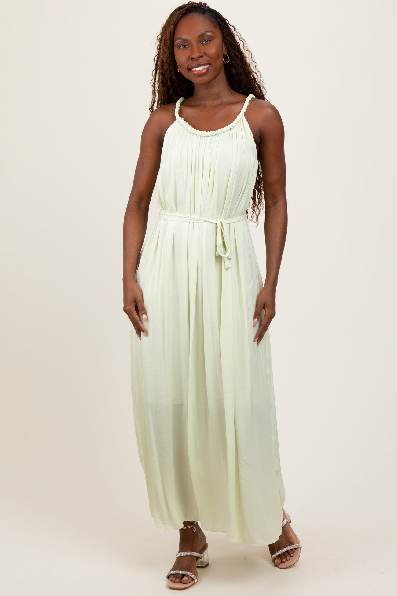 woman wearing a light green sleeveless maxi dress with a gathered bodice and adjustable tie waist