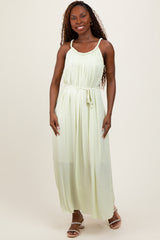 woman wearing a light green sleeveless maxi dress with a gathered bodice and adjustable tie waist
