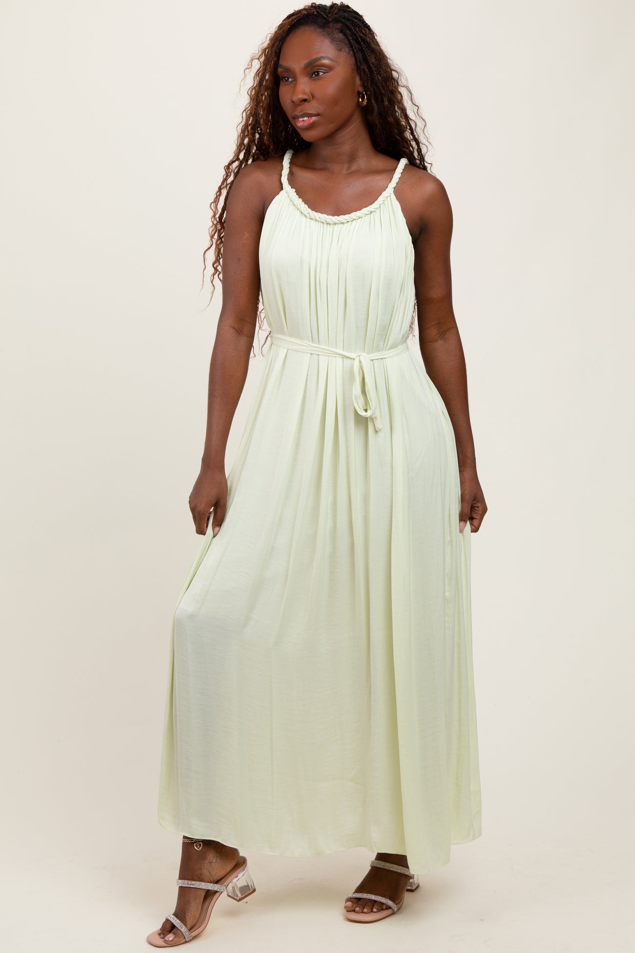 woman wearing a light green maxi dress with a drawstring waist and spaghetti straps