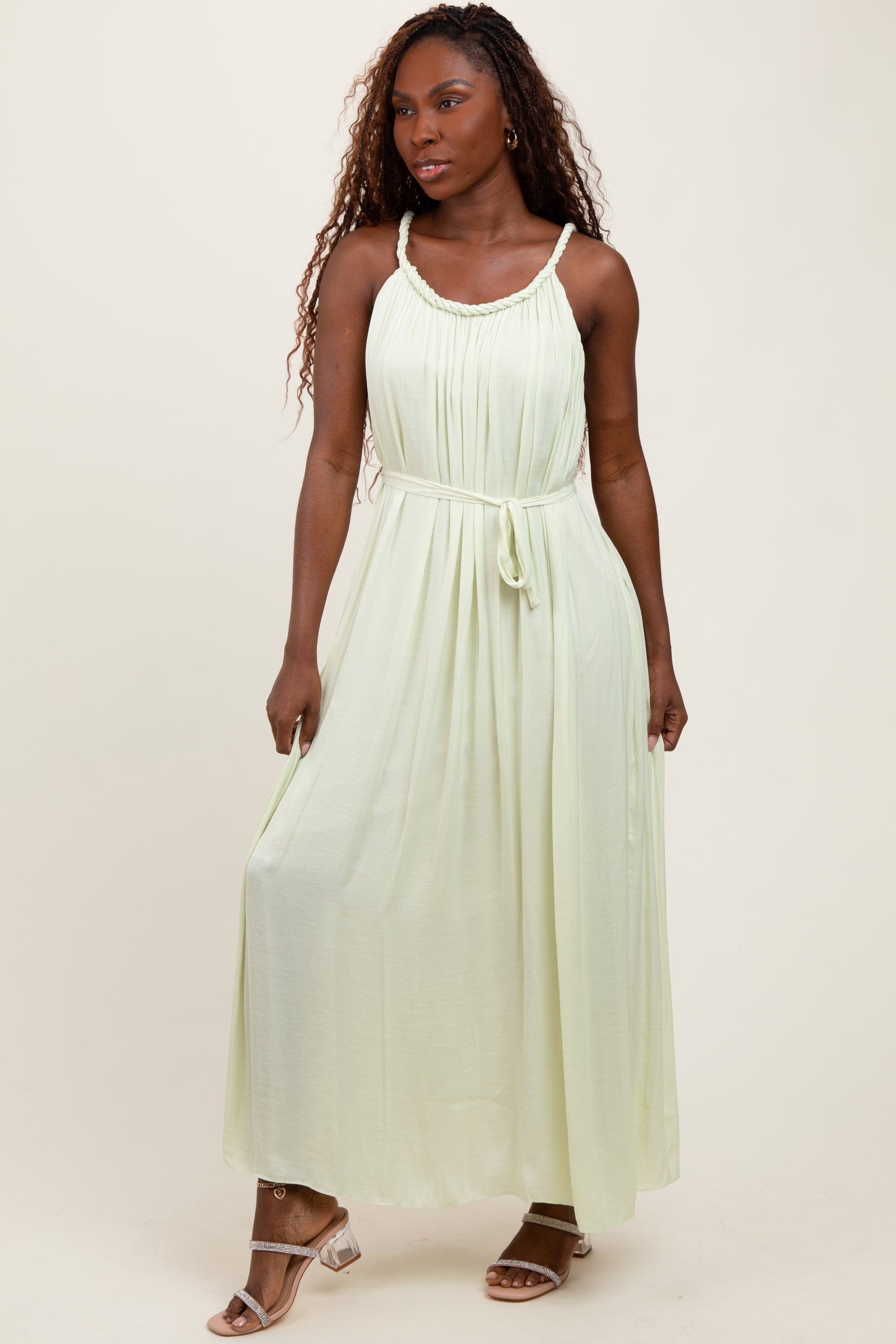 woman wearing a light green maxi dress with a drawstring waist and spaghetti straps
