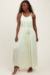 woman wearing a light green maxi dress with a drawstring waist and spaghetti straps