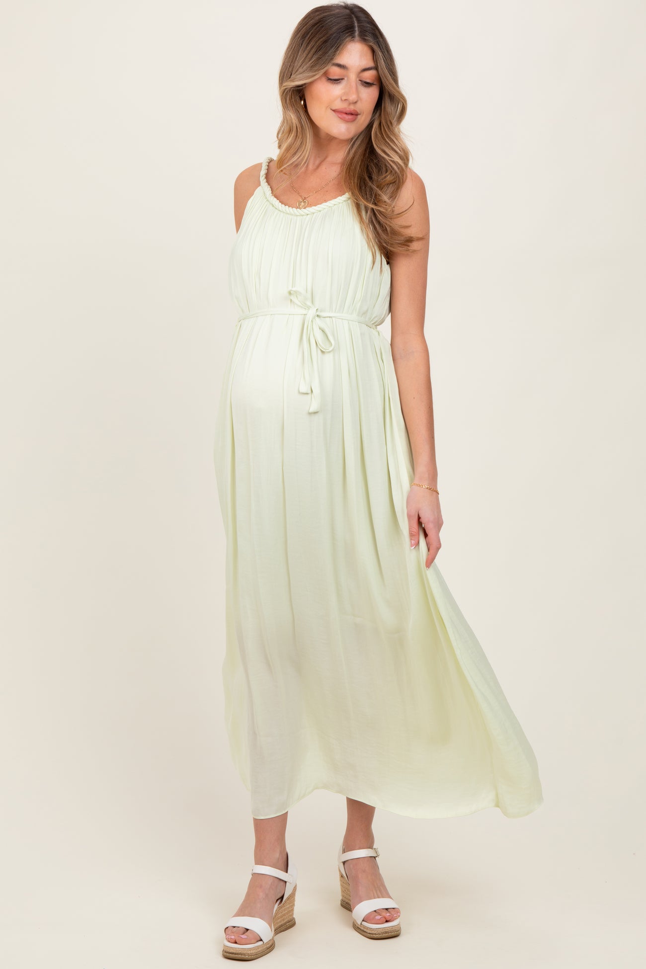 woman wearing a light green maternity maxi dress with a tie waist and a visible baby bump