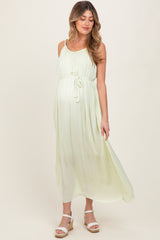 woman wearing a light green maternity maxi dress with a tie waist and a visible baby bump