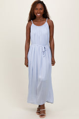 woman wearing a light blue sleeveless maxi dress with a tie waist and gathered neckline