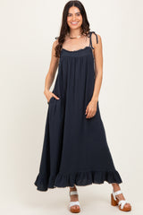 woman wearing a dark navy maxi dress with spaghetti straps and ruffle hem, featuring pockets and a flowy silhouette