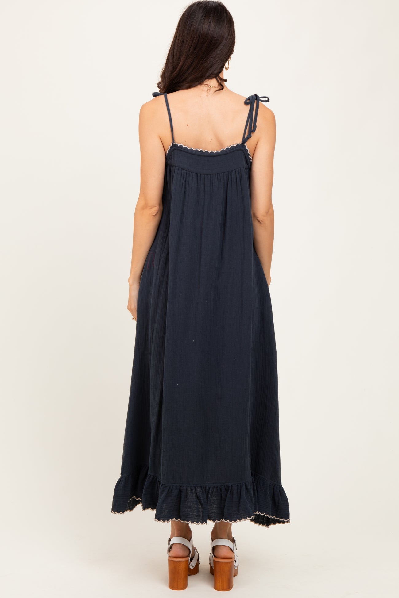woman wearing a navy blue sleeveless maxi dress with adjustable straps and ruffle hem