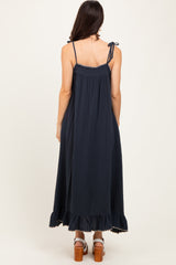 woman wearing a navy blue sleeveless maxi dress with adjustable straps and ruffle hem