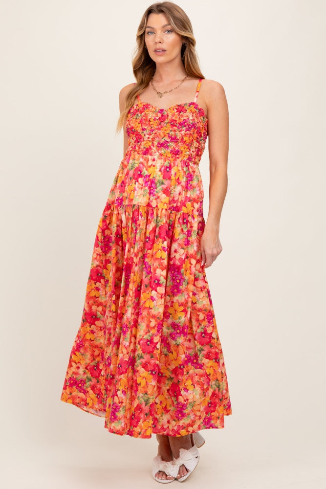woman wearing a vibrant floral maternity maxi dress with a sweetheart neckline and adjustable straps