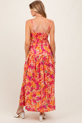 woman wearing a vibrant floral maternity maxi dress with adjustable straps and a smocked back