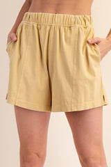 woman wearing yellow relaxed fit shorts with side pockets and an elastic waistband