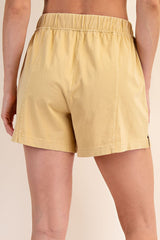 woman wearing yellow high-waisted shorts, showing the back view with elastic waistband and relaxed fit