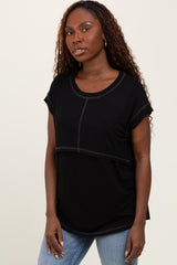 woman wearing a black short sleeve top with a scooped neckline and contrast stitching, paired with light blue jeans