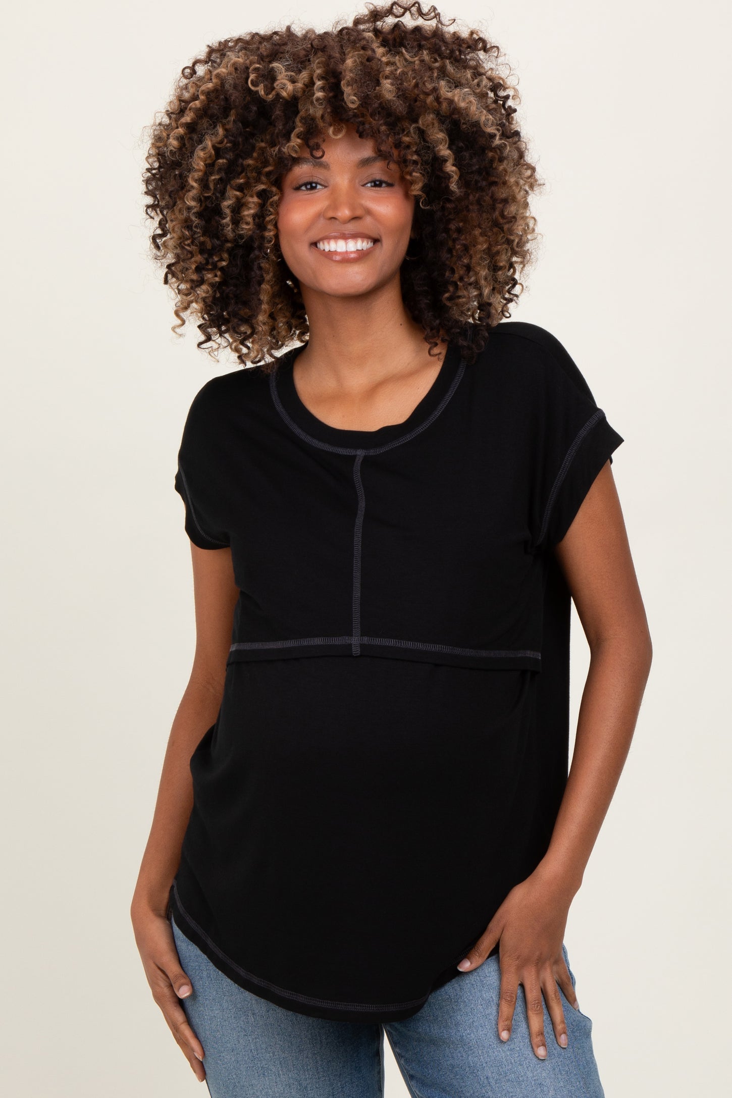 woman wearing a black maternity top with contrast stitching and a relaxed fit, showcasing her baby bump