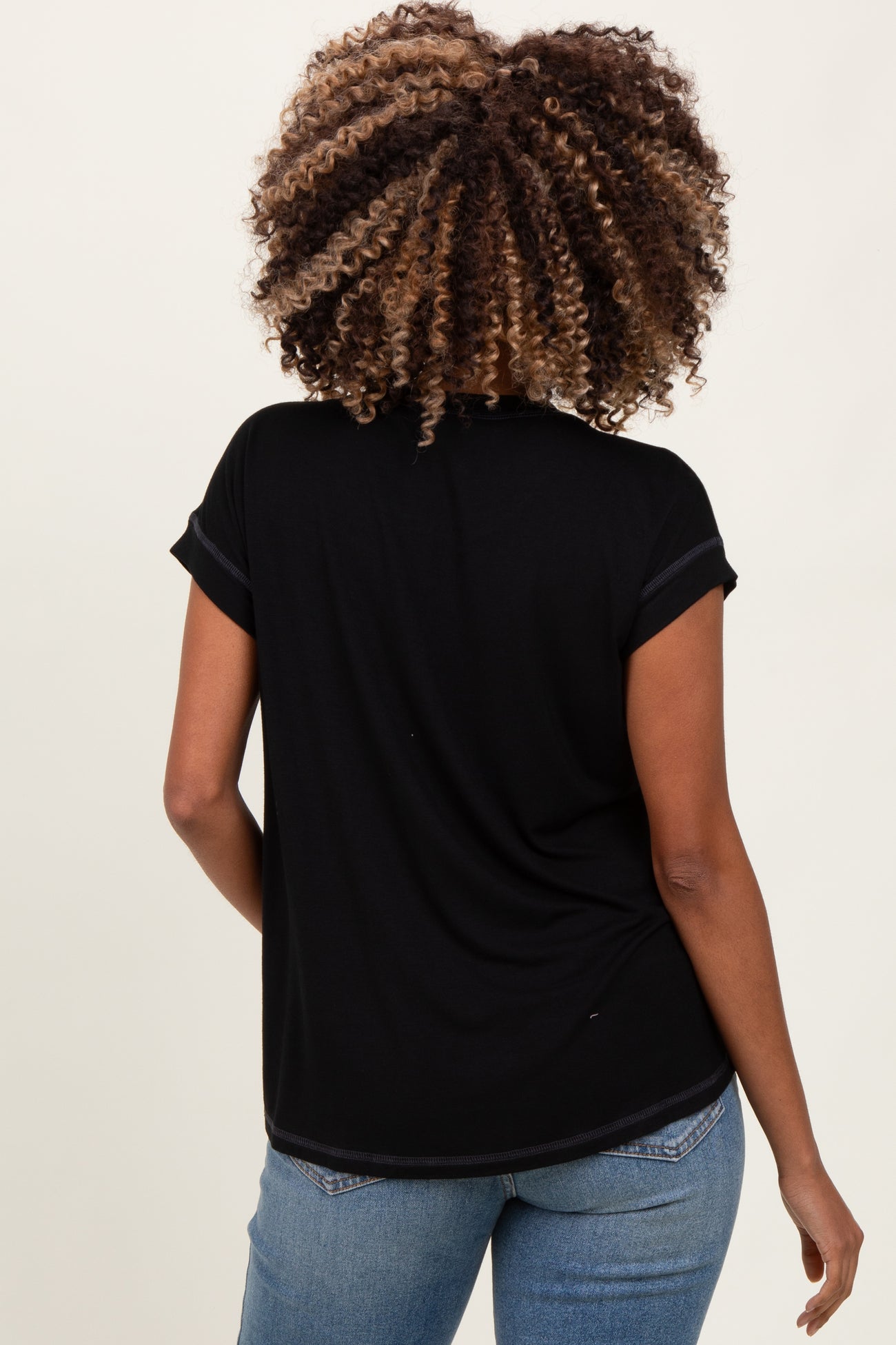 woman wearing a black maternity top with short sleeves and rolled cuffs, facing away from the camera