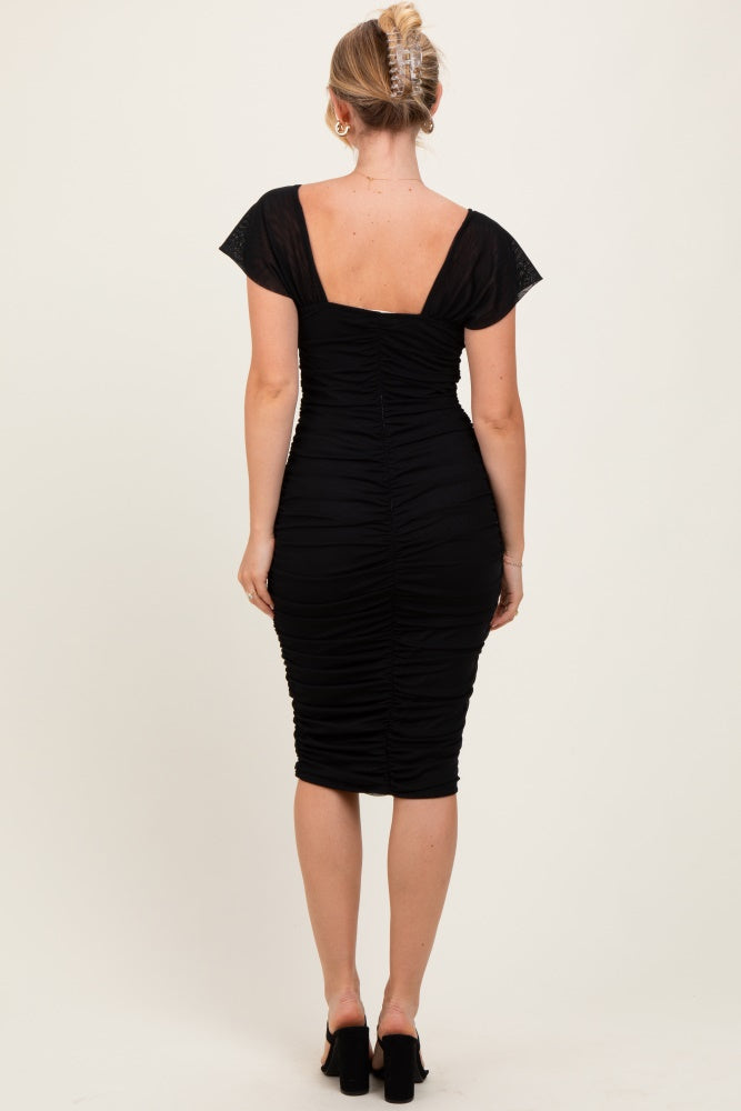 woman wearing a black ruched bodycon dress with cap sleeves, showing the back view