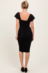 woman wearing a black ruched bodycon dress with cap sleeves, showing the back view