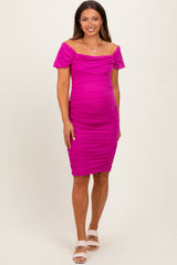 woman wearing a bright pink off-the-shoulder maternity dress that highlights her baby bump