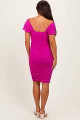 woman wearing a hot pink maternity dress with ruching detail and short puff sleeves, showcasing her baby bump from the back