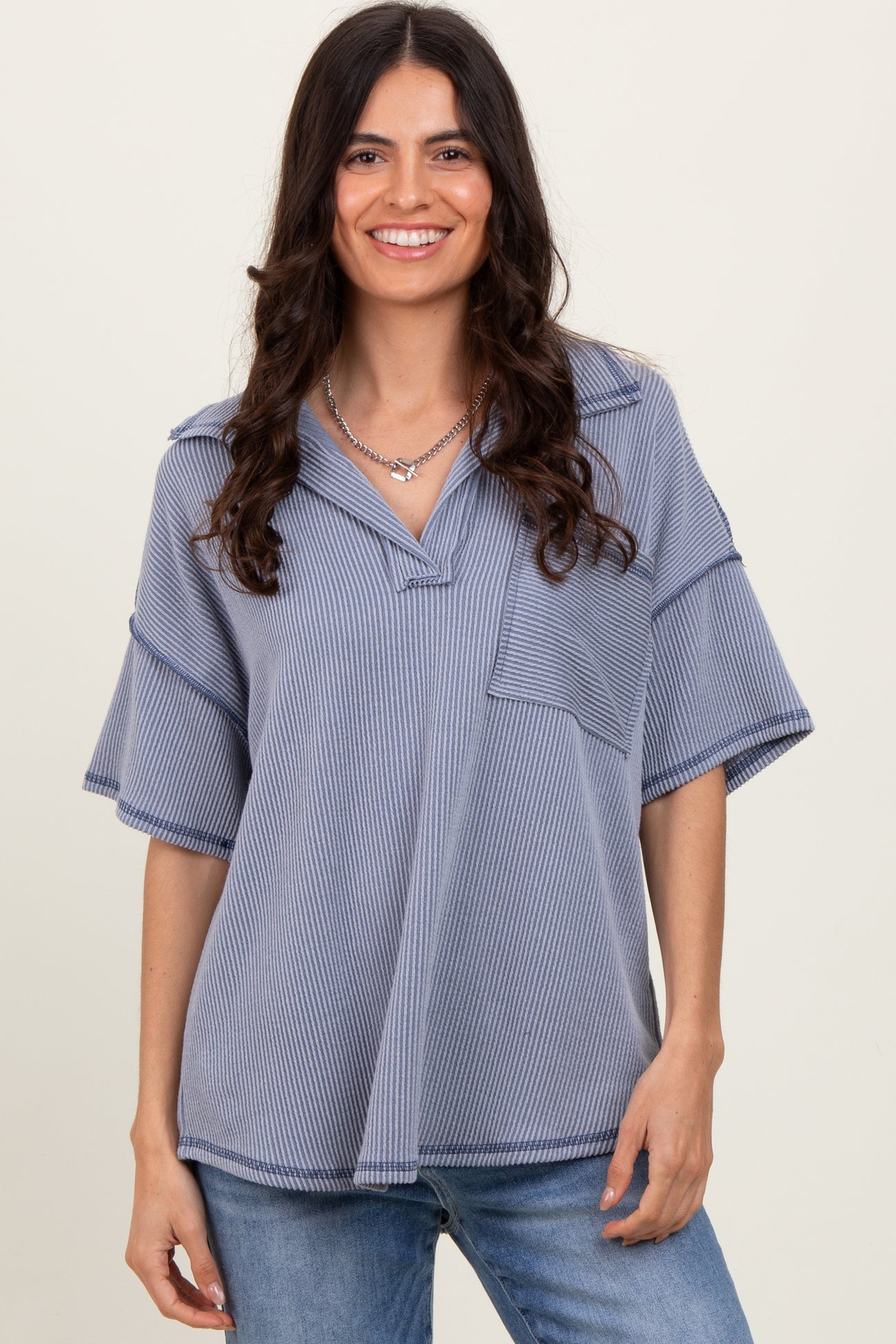 woman wearing a blue striped oversized short sleeve top with a v-neck and front pocket