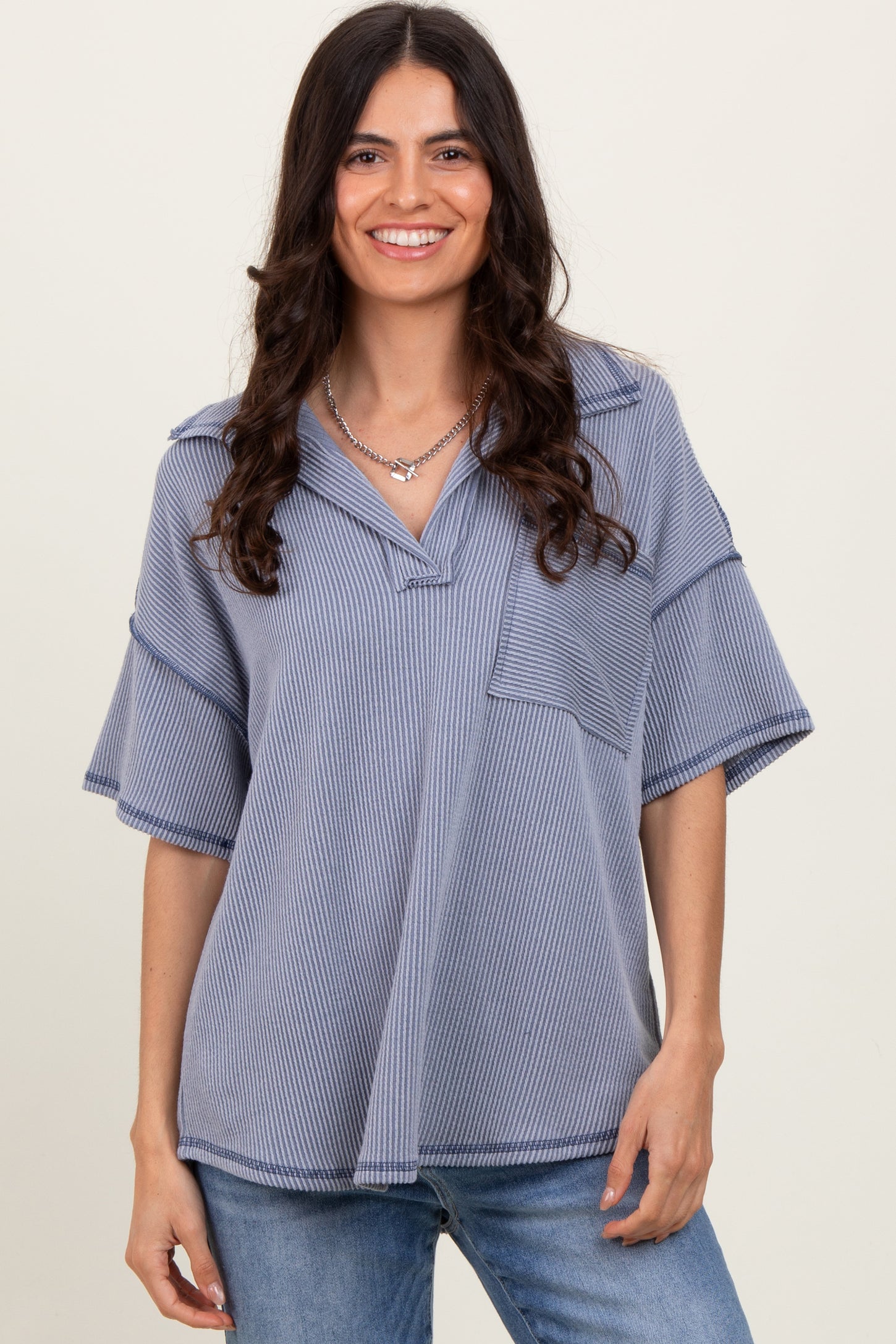 woman wearing a blue striped oversized short sleeve top with a v-neck and front pocket