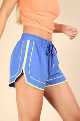 woman wearing blue athletic shorts with yellow trim and a drawstring waist