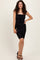 woman wearing a black strapless ruched bodycon dress, holding a small clutch and smiling with curly hair