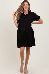 woman wearing a black short sleeve maternity dress with a v-neck and puff sleeves, showcasing her baby bump