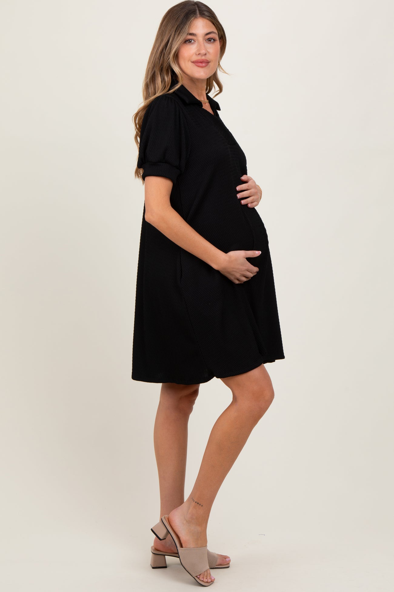 woman wearing a black short sleeve maternity dress and holding her baby bump