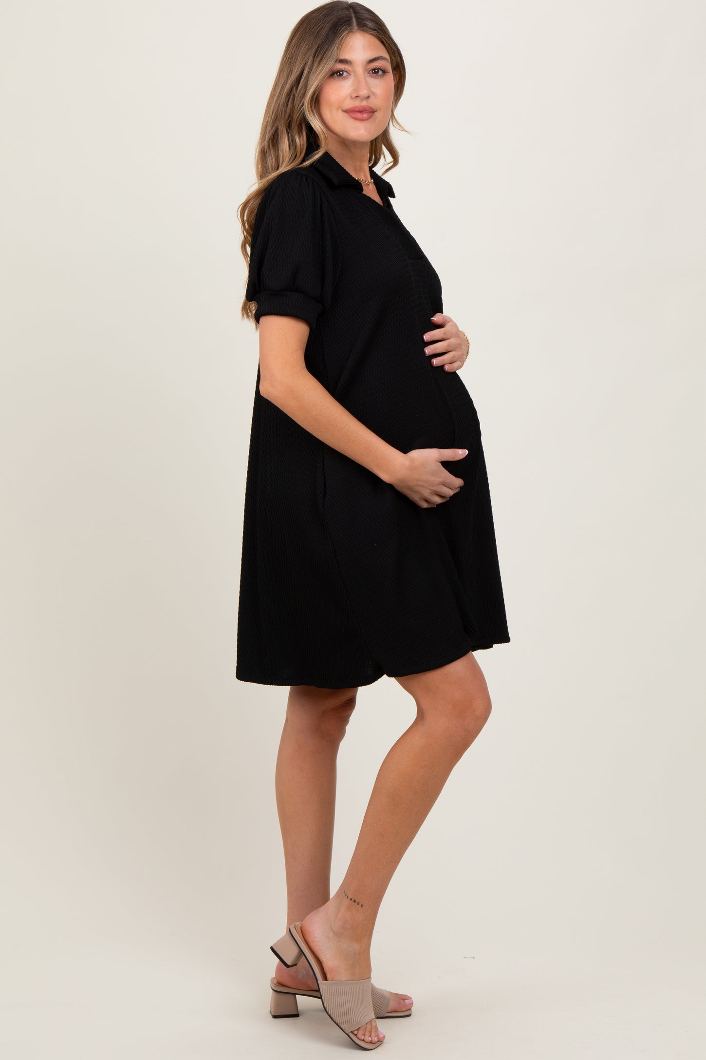 woman wearing a black short sleeve maternity dress and holding her baby bump