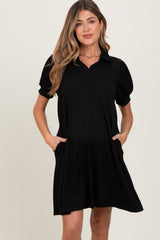 woman wearing a black short sleeve maternity dress with a collar and side pockets, showing a baby bump