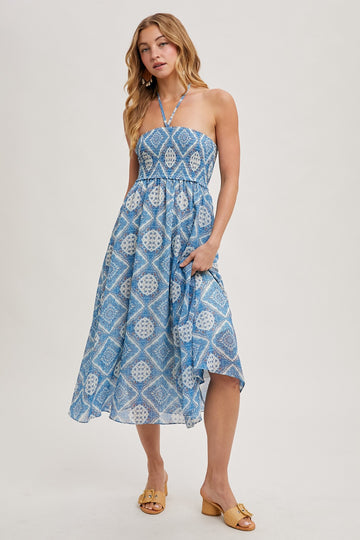 woman wearing a light blue patterned halter neck dress with a flowing skirt and minimal accessories