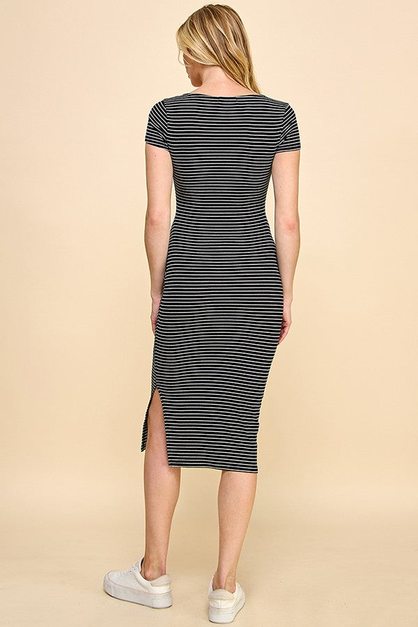 woman wearing a black and white striped midi dress with short sleeves and a side slit, photographed from the back