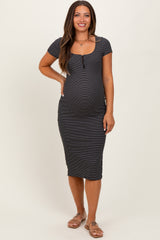 woman wearing a black and white striped maternity dress with a scoop neckline and short sleeves, showing her baby bump