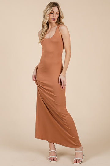 woman wearing a fitted tan maxi dress with thin straps and a scoop neck