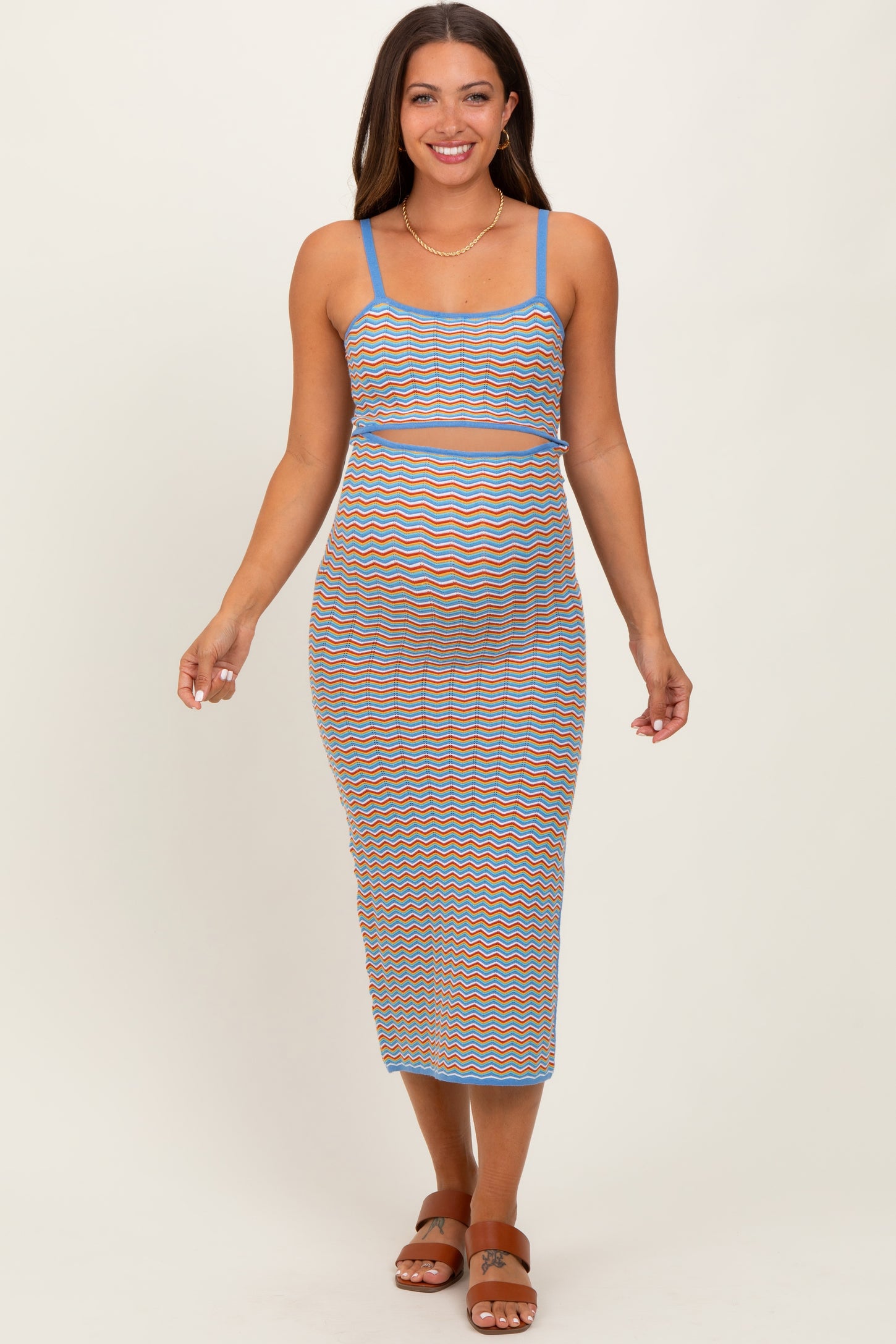 woman wearing a multicolored striped maternity dress with a fitted silhouette and spaghetti straps, showing her baby bump