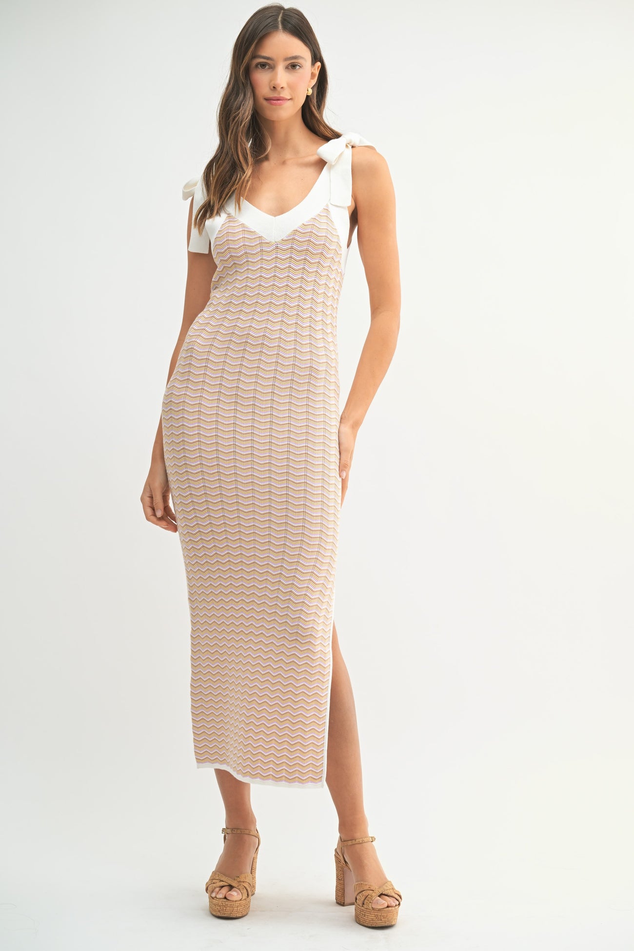 woman wearing a cream and beige knit maxi dress with tie shoulder straps and a v-neckline