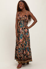woman wearing a black floral maxi dress with a flowy silhouette and spaghetti straps, smiling with hands on hips