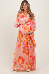 woman wearing a pink floral maternity maxi dress and holding her baby bump