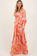 woman wearing a pink floral maxi dress with long sleeves and a tie waist detail