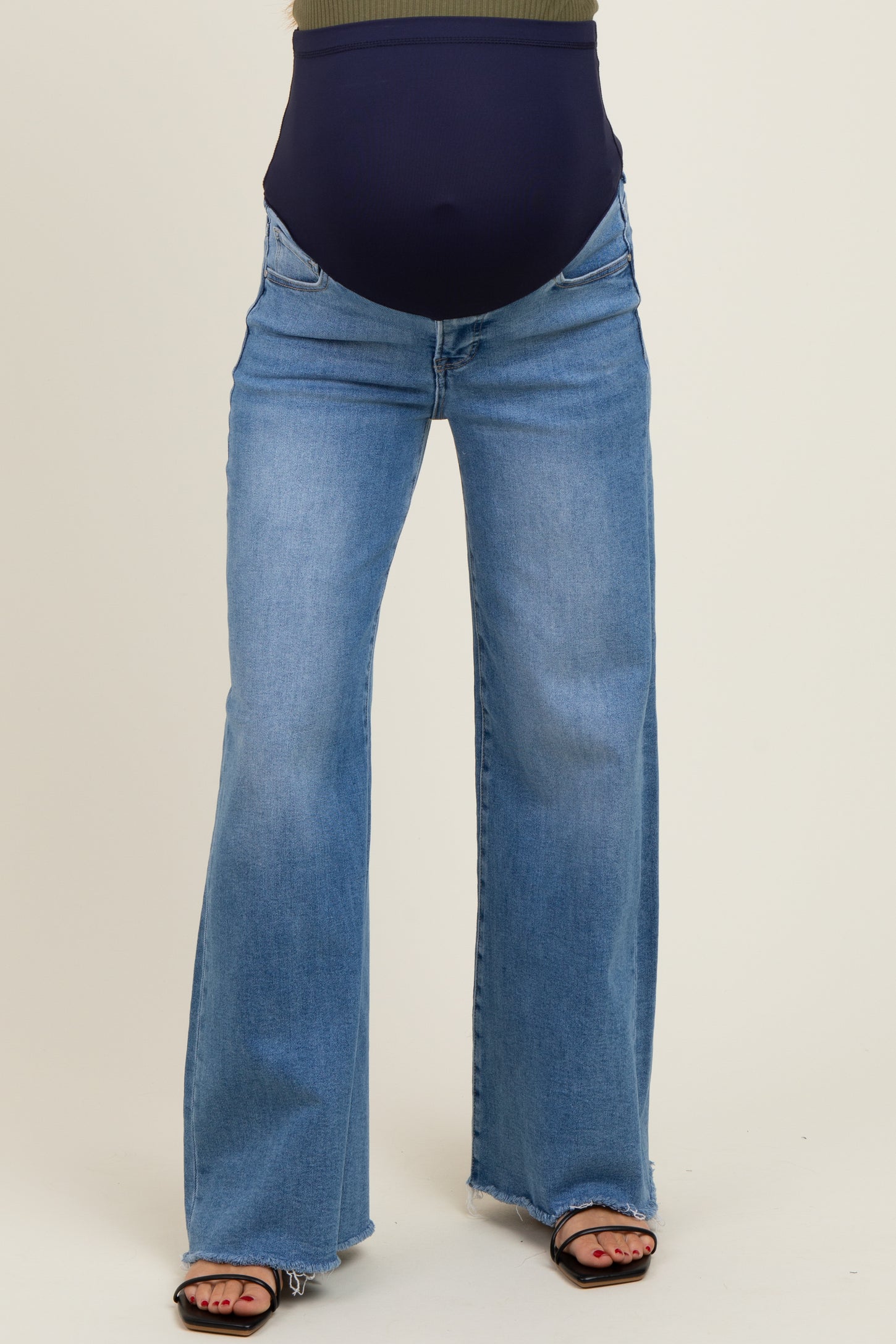woman wearing a pair of light blue maternity flared jeans with a navy waistband and sandals