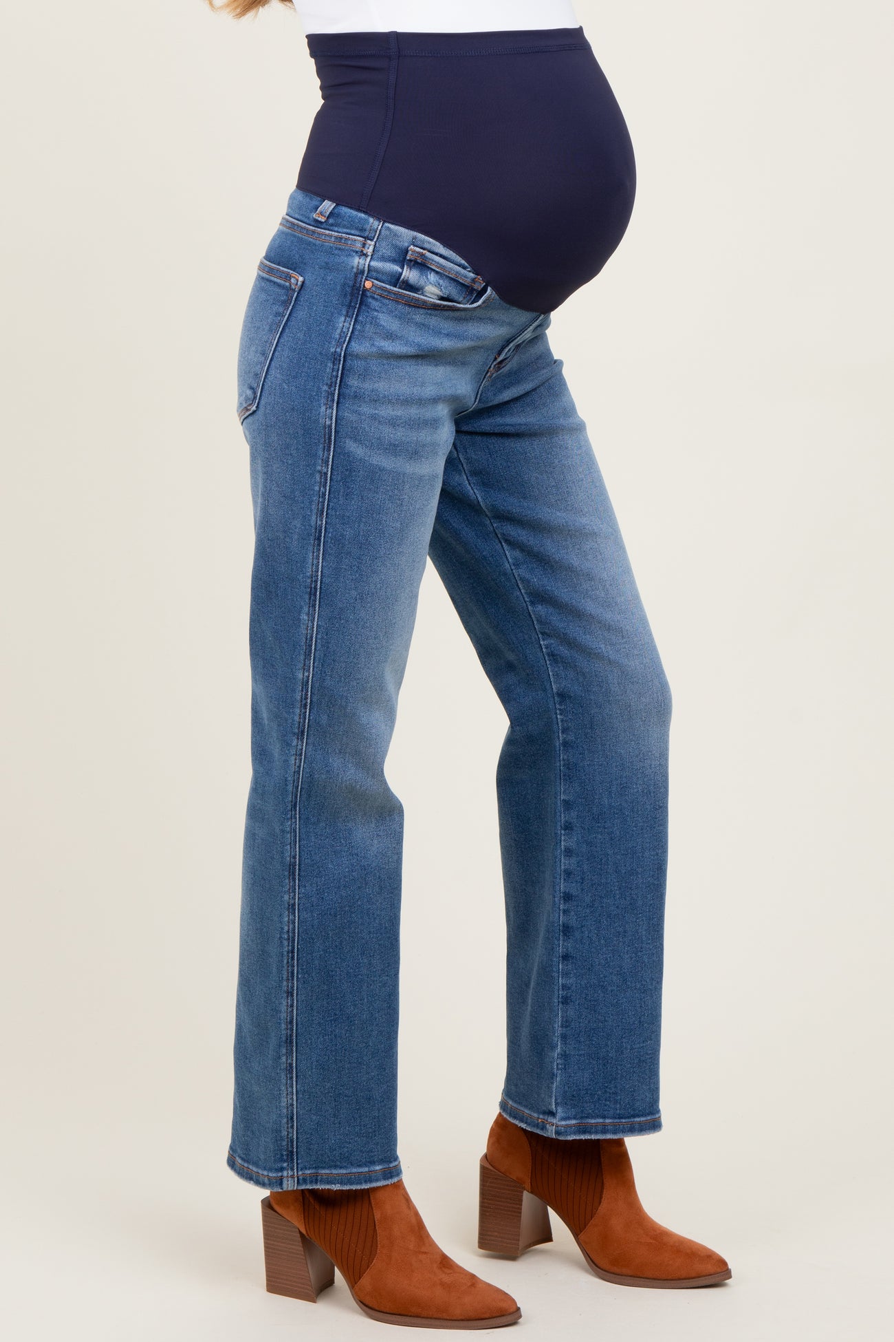 woman wearing a pair of blue maternity jeans with a supportive belly panel and a stylish boot cut, showcasing her baby bump