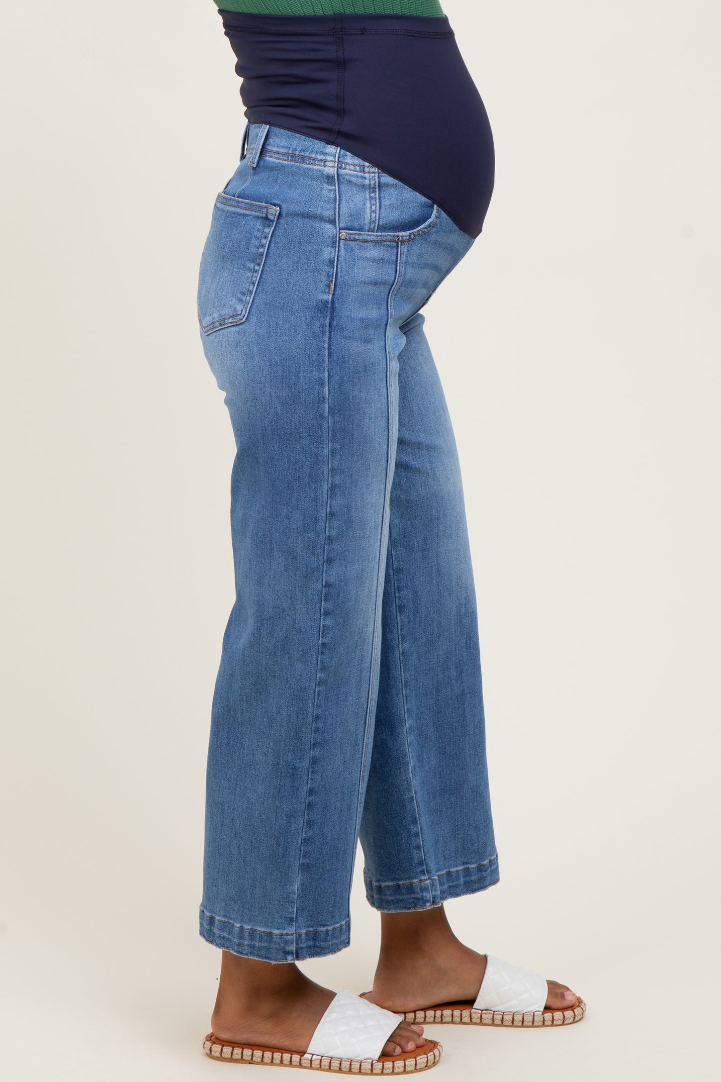 woman wearing light blue maternity wide-leg jeans, showcasing a visible baby bump