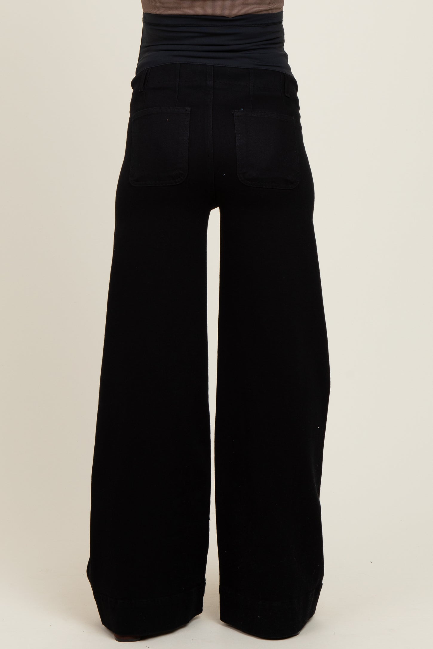 woman wearing black wide-leg maternity pants, seen from the back, with a fitted top above