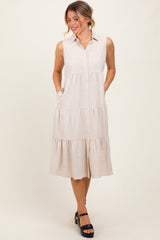 woman wearing a beige sleeveless button-up tiered midi dress with side pockets and black platform heels